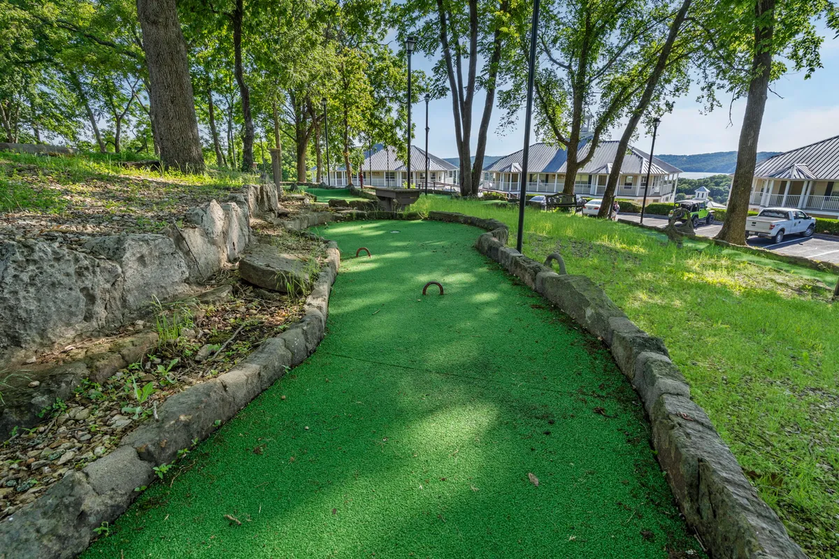 A cheerful mini-golf course is nestled amidst natural landscaping and green grass. Families and friends can be imagined enjoying the playful, interactive layout, surrounded by the beauty of the outdoors.