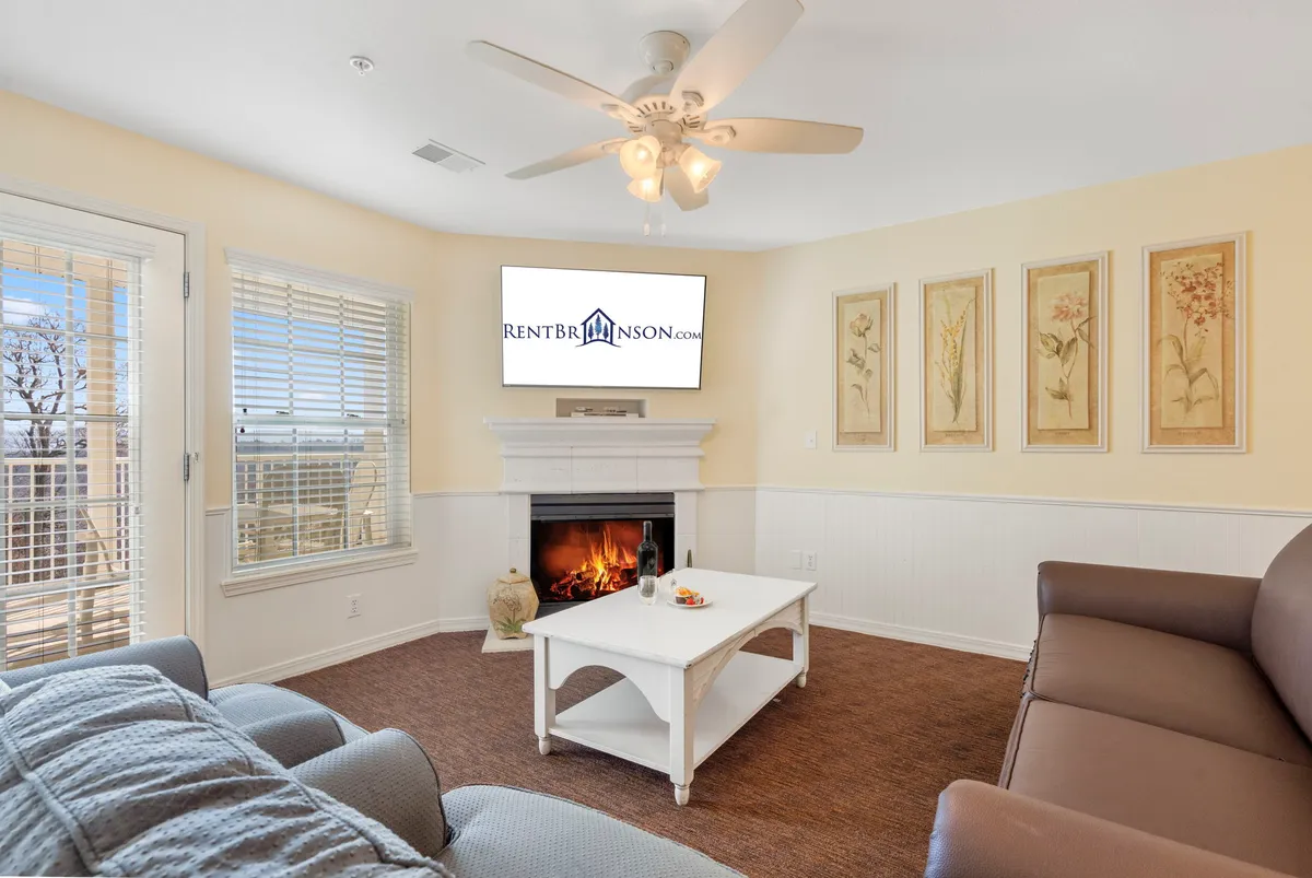 A welcoming living room featuring a fireplace, coffee table, comfortable seating, and tasteful wall art. The space is arranged for both relaxation and socializing, with the fireplace serving as a warm focal point ideal for cozy autumn and winter evenings.
