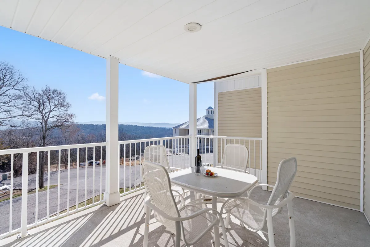 A serene outdoor setting featuring a table with chairs on a patio, a bottle of wine, and expansive scenic views of Table Rock Lake. The ambiance suggests a tranquil spot for relaxing, dining outside, or enjoying the sunset over the water.