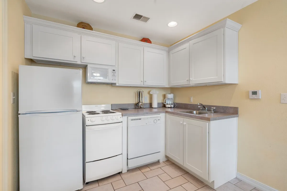 A modern kitchen with white cabinetry, stainless steel appliances, and a spacious countertop is visible. The setup is inviting and functional, perfect for preparing and sharing meals with loved ones.