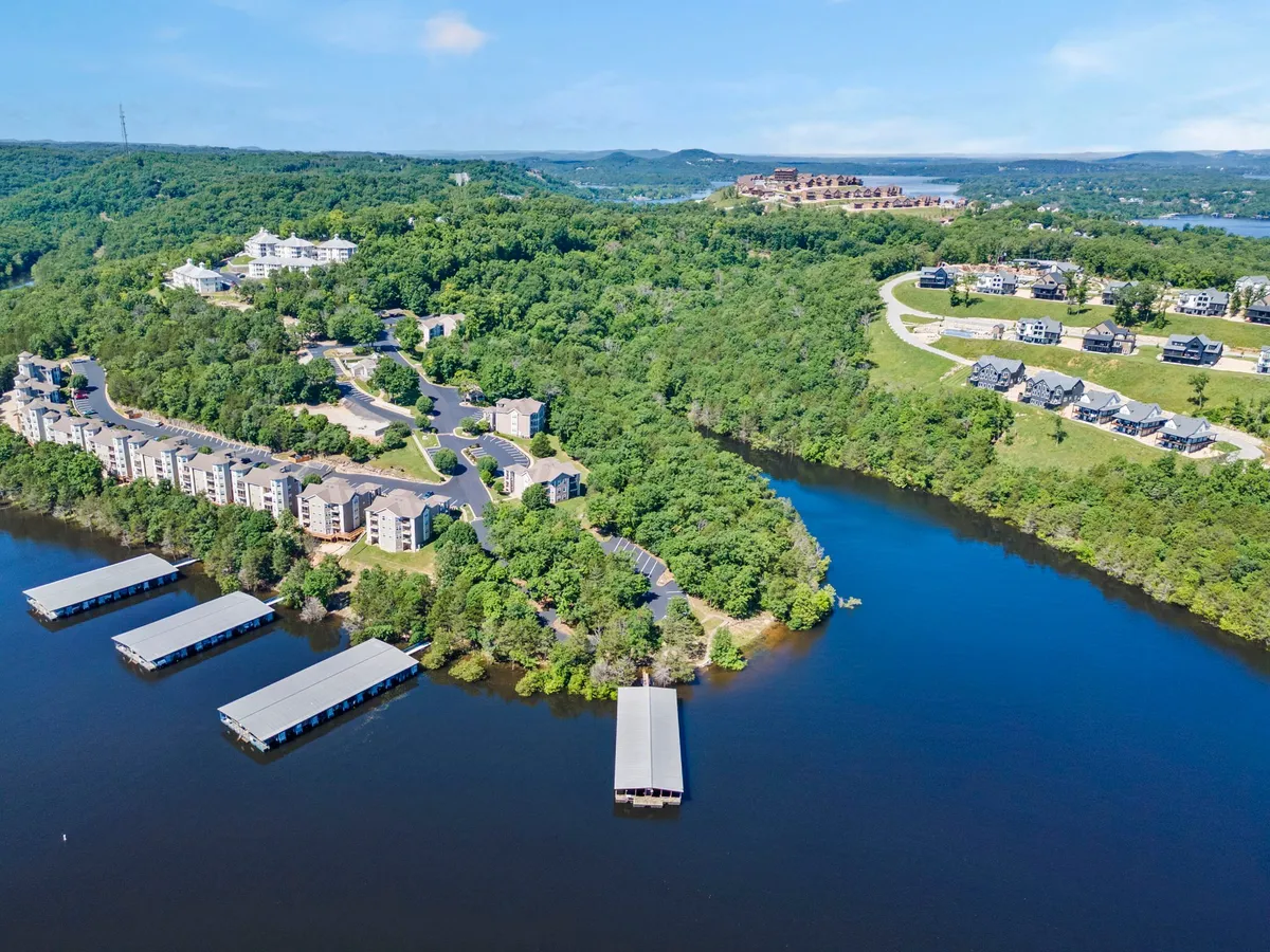 A broad lakeside view with waterfront properties, docks, lush greenery, and hillside homes along Table Rock Lake. The image exudes tranquility and offers a sense of the area's natural beauty and opportunities for boating or leisurely walks.